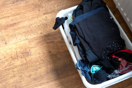 clothes in a full laundry basket on a laminaat floor, top view close-upの写真素材