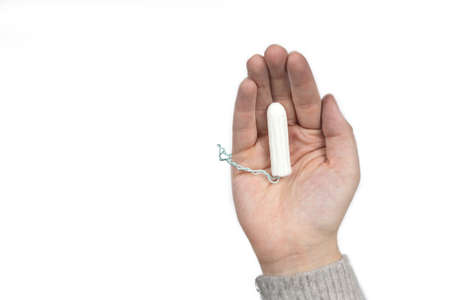 White clean tampon on woman's hand isolated on a white background. Menstruation time. Hygiene and protection. close-upの写真素材