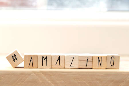 Wooden cubes with a hashtag and the word amazing, social media concept background