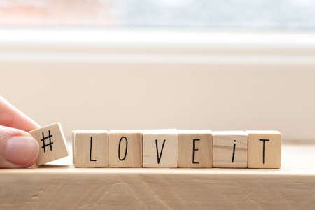 Wooden cubes with a hashtag and the words love it, social media concept background