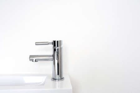 Silver metal faucet on white wall, new clean modern sink background