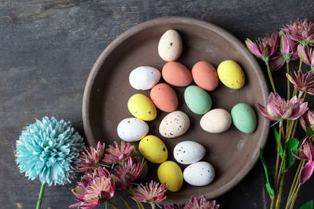 Easter eggs painted in pastel colors on a vintage wooden background texture, concrete look plate...