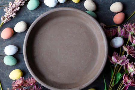 Grey Ceramic Plate with painted Easter Eggs of pastel colors on vintage wooden background. Happy Easter card concept, minimalistic design, top viewの写真素材