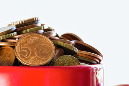 Saved Money in a colorful red mug to Finance Goals overflowing with euro coins, business concept...
