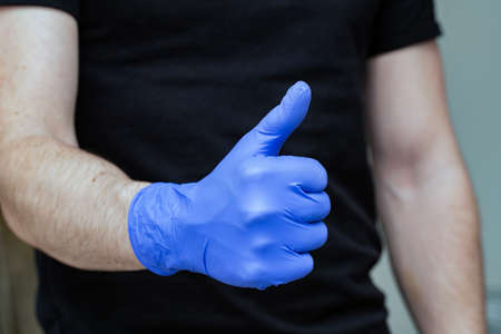 Person with blue latex gloves for protection coronavirus with thumbs up, Covid-19 self isolation or quarantine at home support doctors and nursesの写真素材