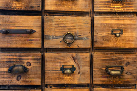 Old antique wooden drawers, rows of little drawers in an old furniture module, Storage archive wooden background texture vintage look close-upの写真素材
