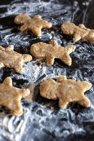 Person baking Gingerbread man cookies, Person hands in dough with flower in cozy kitchen close-up