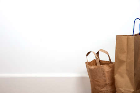 Close up of brown shopping bag against white wall on wooden floor, retro design space for textの写真素材