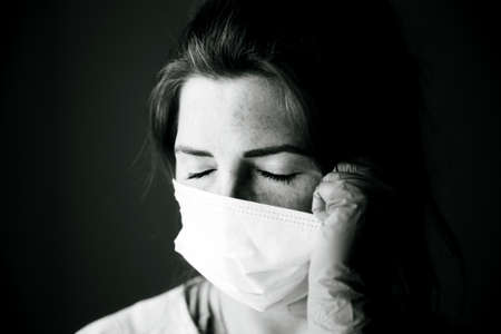 Young woman wearing protection mask against Covid-19, Coronavirus looking depressed and isolated, black and white portrait virus conceptの写真素材