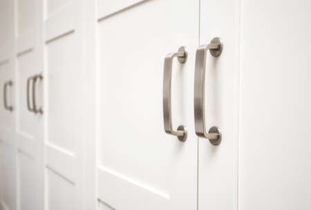 White wooden cupboard doors modern interior, storage or wardrobe closed with metal handlesの写真素材