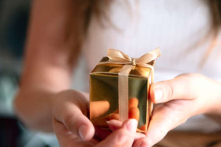 Womens hands holding gold gift box, Holiday present,birthday,Christmas, Father or Mothers,...