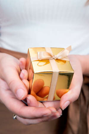 Women's hands holding gold gift box, Holiday present,birthday,Christmas, Father or Mother's,...
