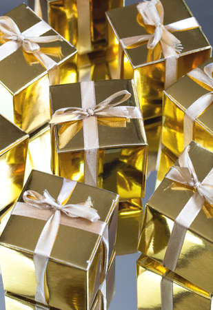 Group of gold sparkling gift boxes on grey background with reflection. A set of gold gift boxes for present, suprise,birthday,Christmas concept beautyの写真素材