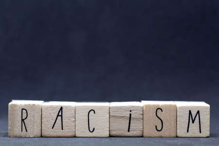 Wooden cubes with the word racism on dark background, black lives matter conceptの写真素材