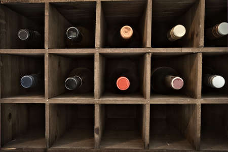 Collection of wine in wooden wine rack in a wine cellar, retro vintage wooden rack design...