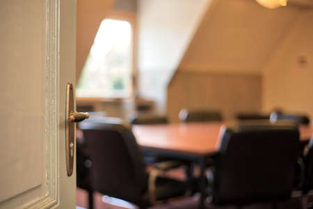 Door with handle opening to a blurred modern meeting room, office concept background emptyの写真素材
