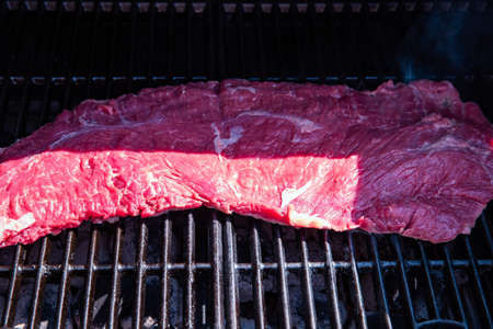 Beef steak on the grill, barbecue bavette in the garden close up, grilled beef outdoors in the summerの写真素材