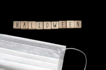 Halloween dark black background with wooden cubes written Halloween and a safety mask for...