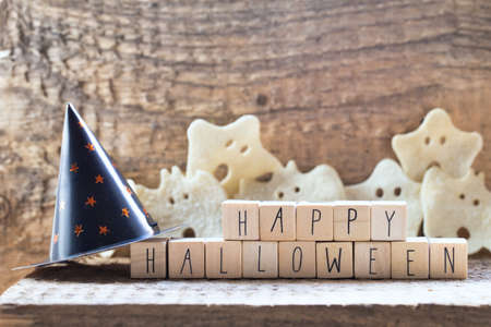 Words Happy Halloween on wooden cubes with group of scary ghost on wooden background, autumn mood horror halloween concept with witch hatの写真素材
