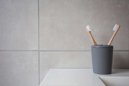 Eco Friendly bamboo natural organic toothbrushes in grey holder, with natural colored stone tiles bathroom wall background textureの写真素材