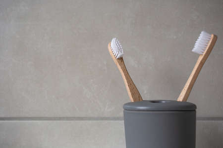 Eco Friendly bamboo natural organic toothbrushes in grey holder, with natural colored stone tiles bathroom wall background textureの写真素材