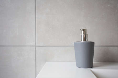 Gray soap dispenser for liquid soap, natural stone tiled bathroom background texture modern designの写真素材