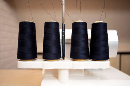 Black thread bobbins on modern overlock white sewing machine, professional sewing machine