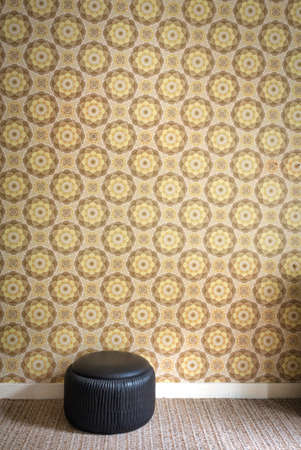 Old room with cheerful vintage wallpaper on the wall and black old pouf, retro interor background texture, copy spaceの写真素材