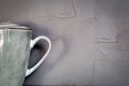Ceramic mug with white foam gray natural stone design with concrete wall background, coffee or tea concept,copy spaceの写真素材