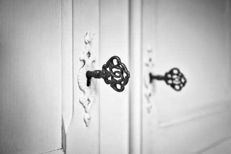 Old vintage doors with antique skeleton keys in lock, retro background texture black and whiteの写真素材