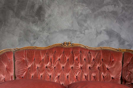 Antique luxury sofa detail against concrete wall background texture, beautiful vintage design copy spaceの写真素材
