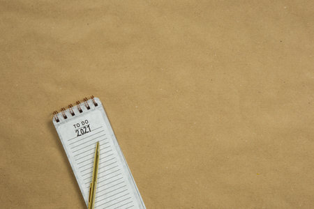 Planning New Year goald on empty notepad in the year 2021, top view on brown background texture, top view copy space, space for text modern designの写真素材