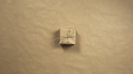 Two gift boxes wrapped in plain brown recycled paper with rope on brown background texture top view,...