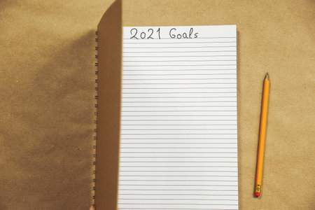 Open Notebook writing 2021 New Year goals Close up on brown background, Business or education...