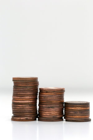 Side view of stacks of coins increasing in height, on white studio background isolated, business and...