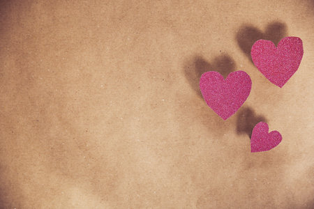 Romantic pink heart on brown plain paper background texture for romantic concept, Valentines Day, Mothers Day other holliday. Copy spaceの写真素材