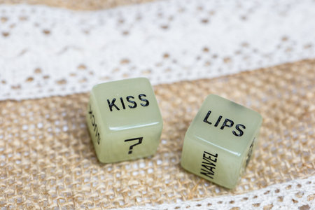 Two erotic dice for sexual game with cotton lace background texture, with the text Kiss lips for Valentines Day,sex,sensual,romantic, love conceptの写真素材