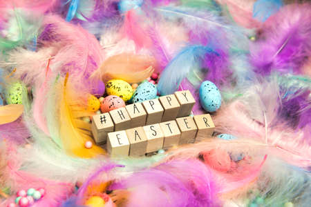Happy Easter written with wooden cubes and hashtag surrounded with beautiful pastel colored...