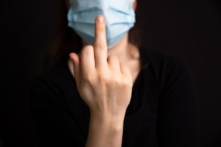 Raise the middle finger for , Female wearing protective medical mask for  dark background, Concept for  and health, Stopの写真素材