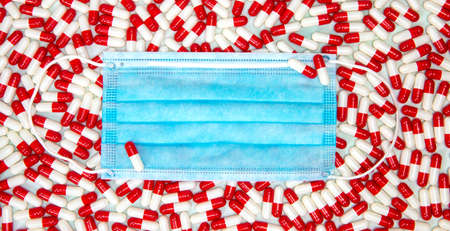 Blue protective face mask for Covid-19 with red and white capsules for medication coronavirus, top...