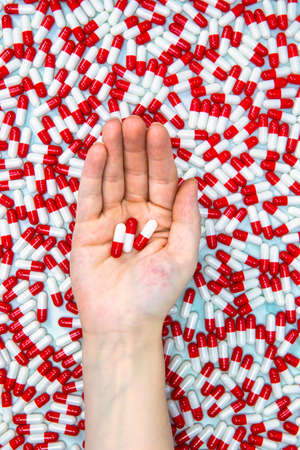 hands holding red and white capsules for medication, vitamin or drugs background on white...