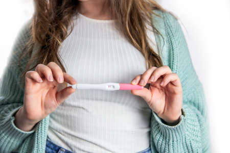 Happy young woman holding a positive pregnancy test close-up bright colors modern stylish design beautiful natureの写真素材