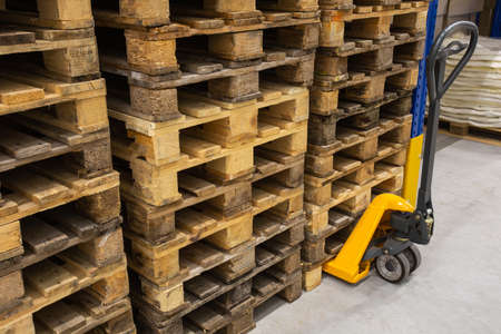 Hand pallet truck with stack of wooden pallets. Warehouse equipment. Transportation of goods in stock.Lifting equipment.の写真素材