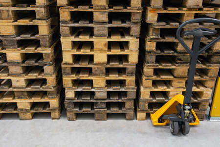 Hand pallet truck with stack of wooden pallets. Warehouse equipment. Transportation of goods in stock.Lifting equipment.の写真素材