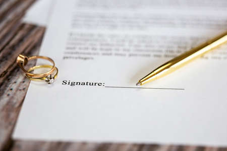 Marriage contract with two golden wedding rings and gold pen, prenuptial agreement, macro close up, sign with signanture,document,agreement conceptの写真素材