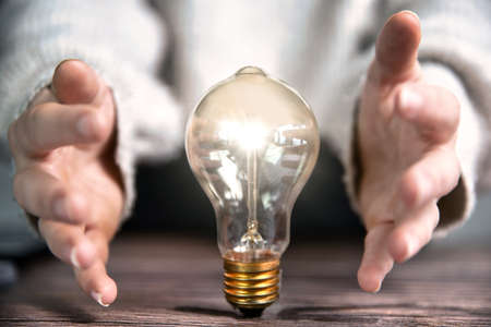 Concept for creativity, brainstorming, business ideas, Glowing lightbulb and hand of business person...