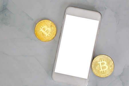 golden bitcoin lies on a smartphone on marble background top view with copy space, cryptocurrency or digital money concept , blacnk mobile phoneの写真素材