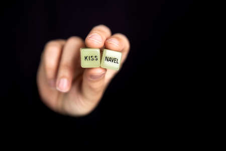 Hand holding two dice with erotic text for sexual game on dark black background with copy space, sex, love, adult, games conceptの写真素材