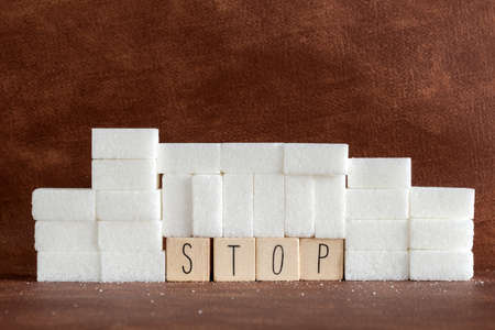 Pile or wall of sugar cubes and stop word in block letters as advise on addiction calories excess...