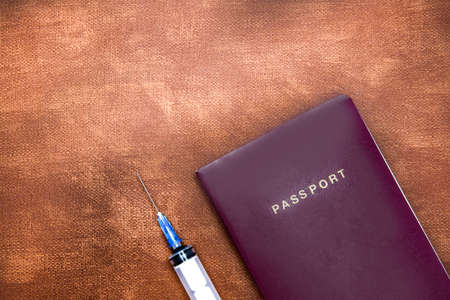 Passport with syringe for vaccination virus on brown leather background with copy space, Concept for Covid-19, traveling and tourism in pandemic time Coronavirusの写真素材